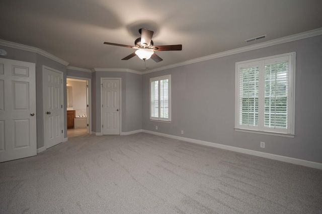 unfurnished bedroom with ornamental molding, baseboards, light colored carpet, connected bathroom, and ceiling fan