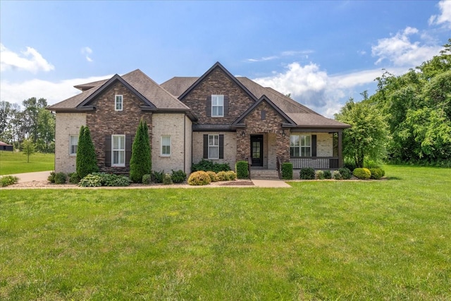 craftsman house featuring a front lawn, brick siding, covered porch, and a shingled roof