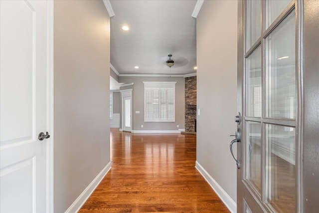 hall with ornamental molding, wood finished floors, baseboards, and recessed lighting