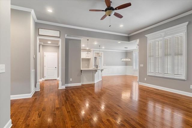 unfurnished living room with ceiling fan, wood finished floors, crown molding, a sink, and recessed lighting