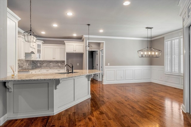 kitchen featuring a sink, crown molding, glass insert cabinets, white cabinets, and backsplash