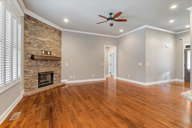 unfurnished living room with a ceiling fan, crown molding, wood finished floors, a stone fireplace, and baseboards