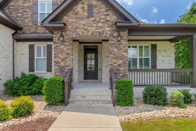 property entrance with covered porch and brick siding