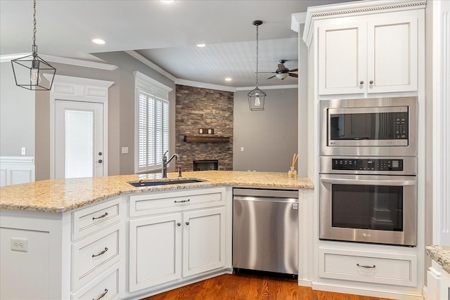 kitchen featuring appliances with stainless steel finishes, a sink, ceiling fan, crown molding, and decorative light fixtures