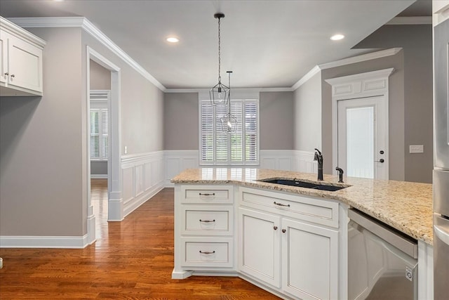 kitchen with a sink, dishwasher, wood finished floors, white cabinets, and a wainscoted wall