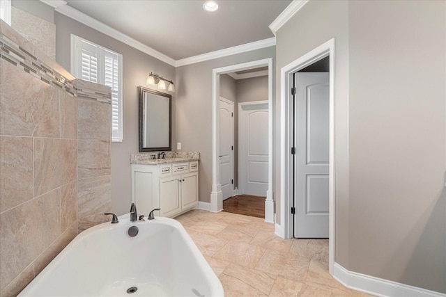 bathroom featuring a freestanding tub, crown molding, vanity, and baseboards