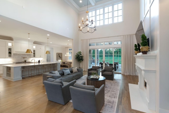 1461 Witherspoon Dr, Brentwood, TN 37027 - living room featuring healthy amount of natural light, a high ceiling, a chandelier, light wood-type flooring, and ornamental molding