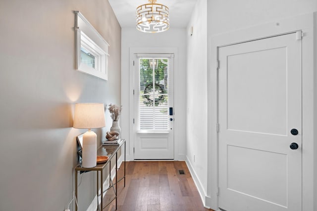 doorway featuring a chandelier, hardwood / wood-style floors, and baseboards
