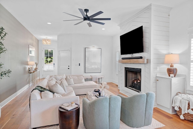 living area featuring a large fireplace, light wood-style floors, ceiling fan, baseboards, and recessed lighting