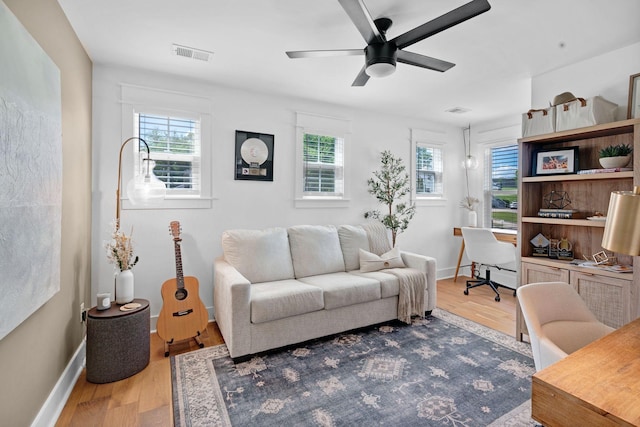 office area with light wood-type flooring, a ceiling fan, and baseboards