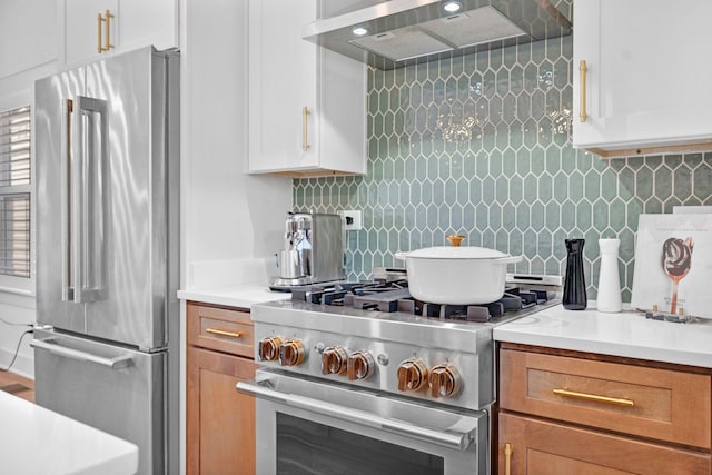 kitchen with appliances with stainless steel finishes, range hood, light countertops, and decorative backsplash