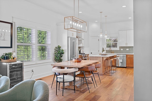 dining area featuring light wood-style floors, recessed lighting, beverage cooler, and baseboards