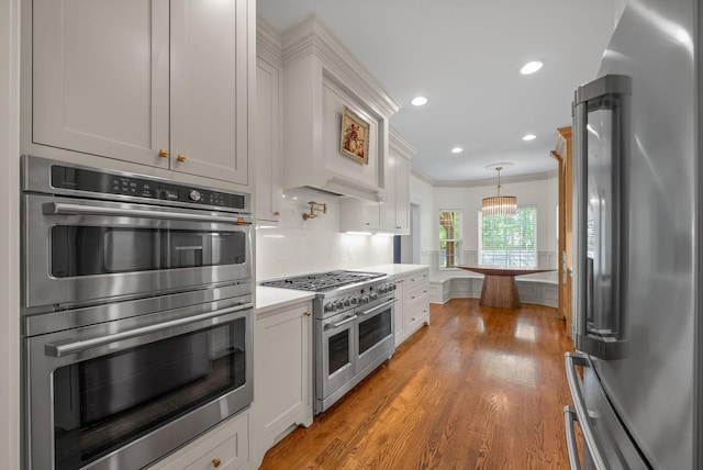 3031 Trice Pl, Lebanon, TN 37087 - kitchen with stainless steel appliances, ornamental molding, light wood-type flooring, light countertops, and white cabinetry