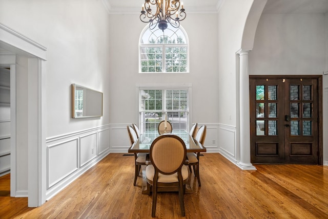 3031 Trice Pl, Lebanon, TN 37087 - dining space featuring arched walkways, decorative columns, light wood-style floors, a chandelier, and a wainscoted wall
