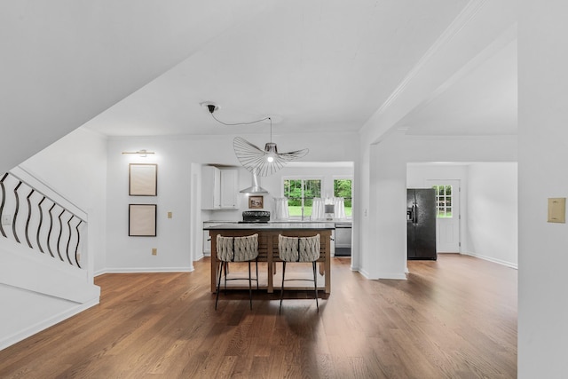 living room featuring wood finished floors, baseboards, crown molding, and stairs