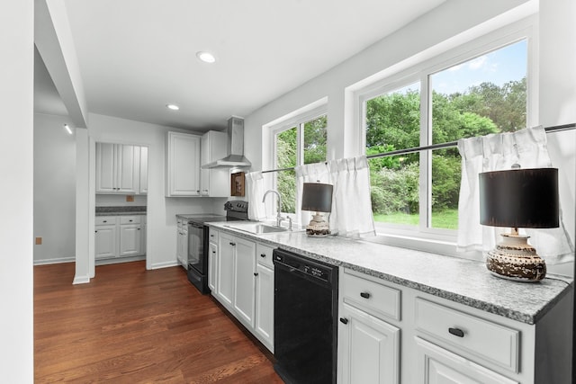 kitchen with black appliances, a sink, wall chimney exhaust hood, dark wood-style flooring, and white cabinetry