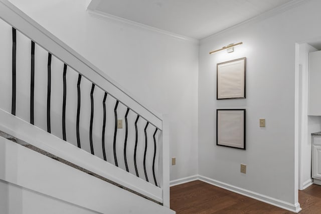 stairway with ornamental molding, wood finished floors, and baseboards