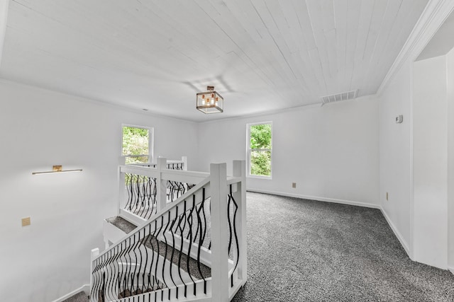 stairway featuring plenty of natural light, carpet, wooden ceiling, baseboards, and ornamental molding