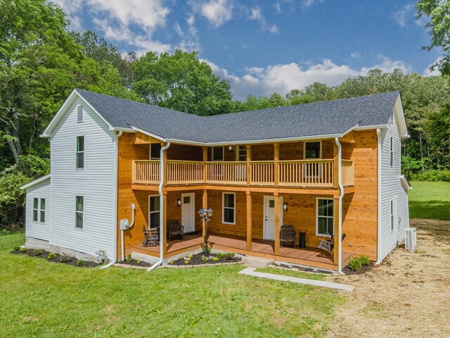 rear view of property with a lawn, a shingled roof, a balcony, central AC unit, and a deck