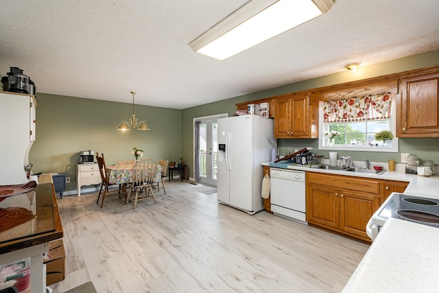 kitchen with white appliances, a sink, plenty of natural light, light wood-style floors, and a textured ceiling