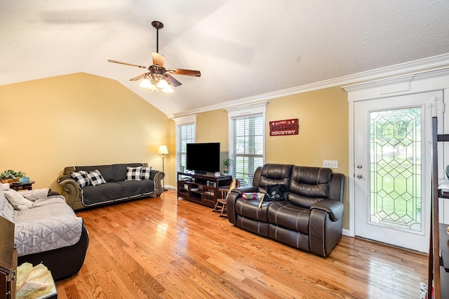 living area featuring ceiling fan, light wood-style flooring, vaulted ceiling, crown molding, and baseboards