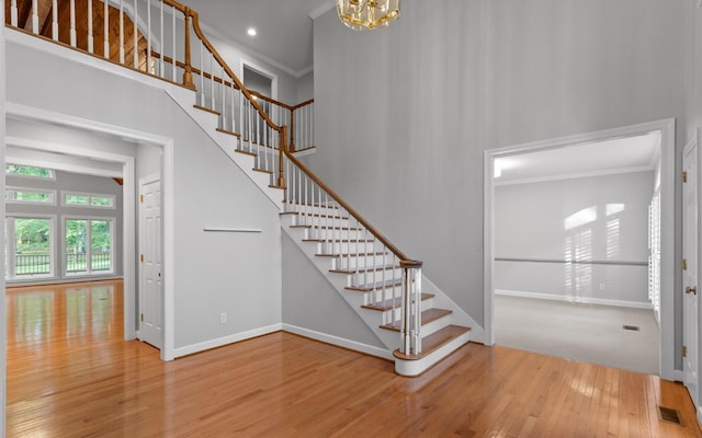 stairs featuring crown molding, wood finished floors, baseboards, a chandelier, and recessed lighting