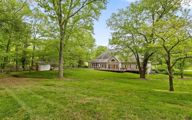 view of grassy yard featuring a storage shed, a wooden deck, and an outdoor structure