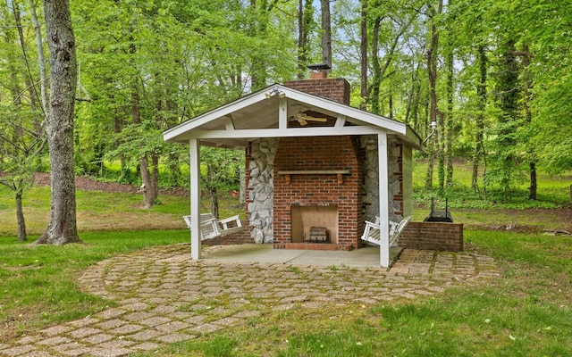 view of patio featuring an outdoor brick fireplace and a gazebo