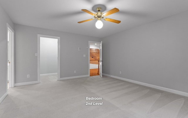 unfurnished bedroom featuring light carpet, a spacious closet, and baseboards