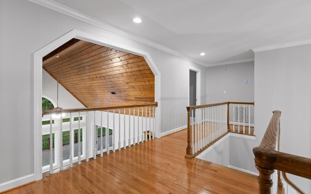 corridor with an upstairs landing, wood finished floors, recessed lighting, crown molding, and baseboards