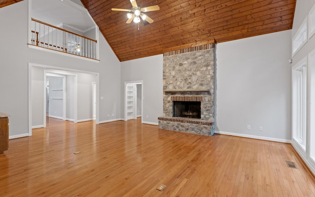 unfurnished living room featuring high vaulted ceiling, ceiling fan, wood finished floors, a large fireplace, and baseboards