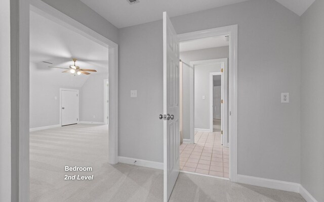 corridor with baseboards, light colored carpet, and lofted ceiling