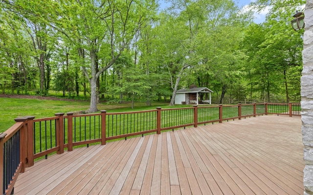 wooden deck featuring a lawn, view of wooded area, and an outbuilding