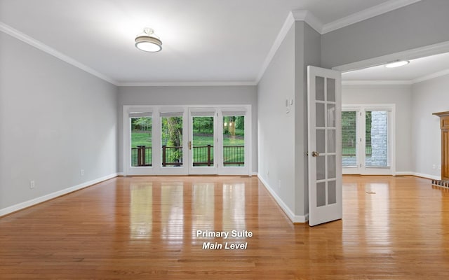 spare room featuring wood finished floors, plenty of natural light, baseboards, and crown molding