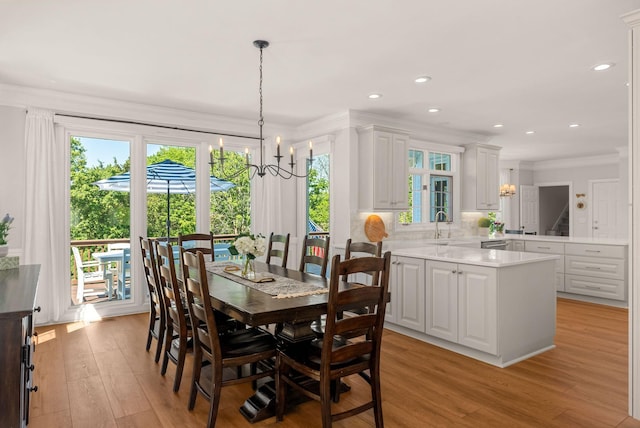 dining room with a chandelier, light wood finished floors, crown molding, and recessed lighting
