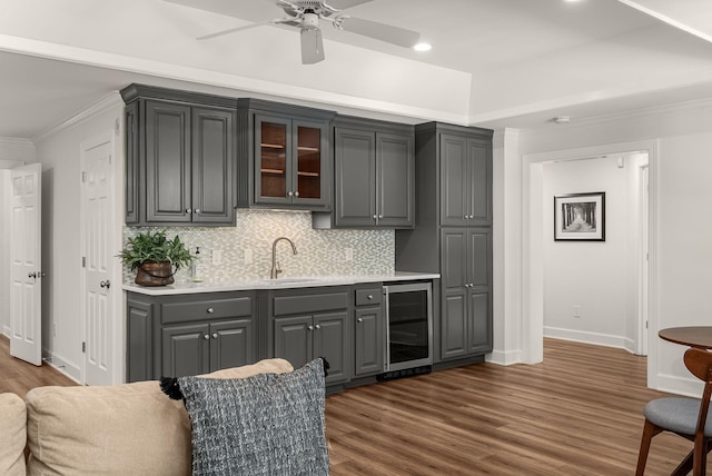 bar area featuring beverage cooler, a sink, crown molding, dark wood-style flooring, and baseboards