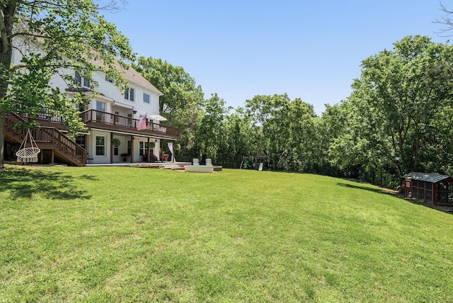 view of green lawn with a wooden deck, stairway, and a patio area