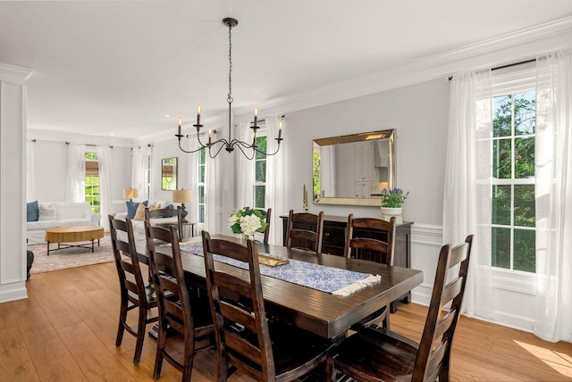 dining area with a chandelier, plenty of natural light, light wood-style floors, crown molding, and wainscoting
