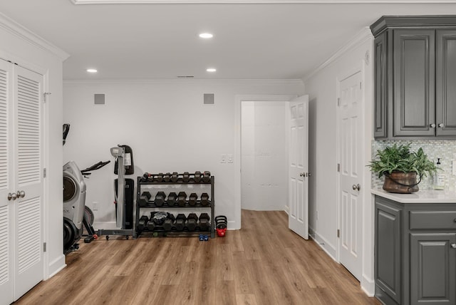exercise area featuring crown molding, light wood-style flooring, and recessed lighting