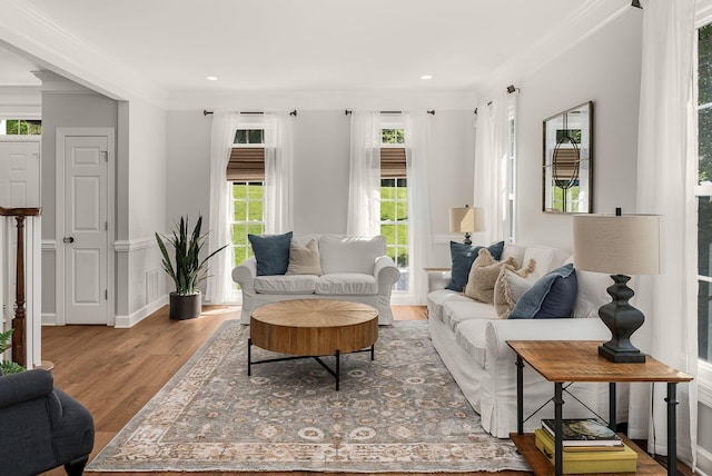 living room with plenty of natural light, wood finished floors, ornamental molding, and recessed lighting