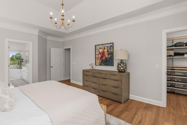 bedroom with a walk in closet, a chandelier, baseboards, wood finished floors, and ornamental molding