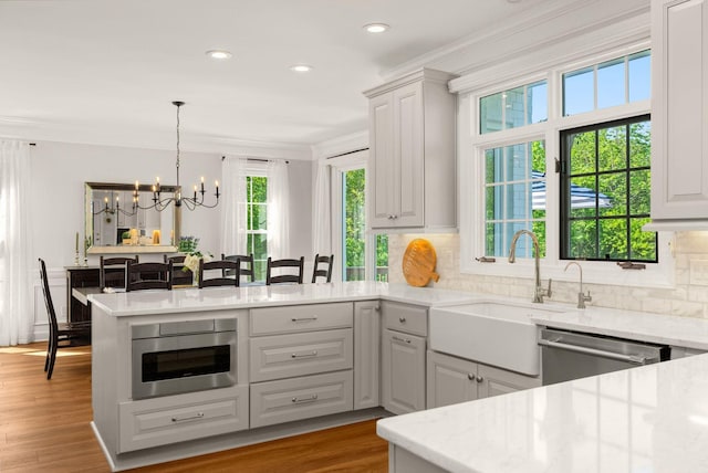 kitchen featuring dishwasher, ornamental molding, a peninsula, a chandelier, and backsplash