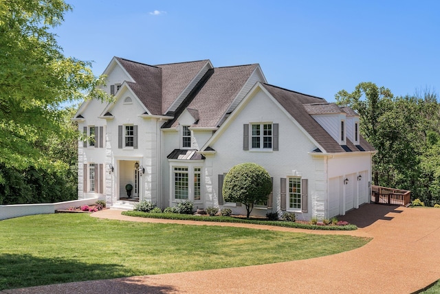 view of front facade featuring driveway, a front yard, and a shingled roof