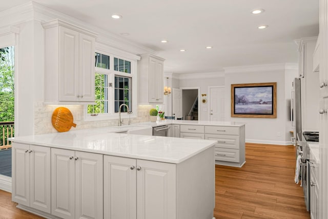 kitchen with a peninsula, plenty of natural light, white cabinets, crown molding, and recessed lighting