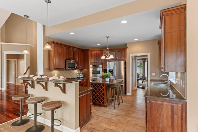 1115 Rossifer Ct, Gallatin, TN 37066 - kitchen featuring appliances with stainless steel finishes, a sink, light wood finished floors, a breakfast bar area, and decorative backsplash
