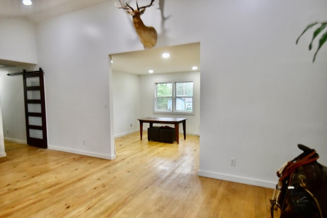 foyer featuring wood finished floors, baseboards, recessed lighting, and a barn door