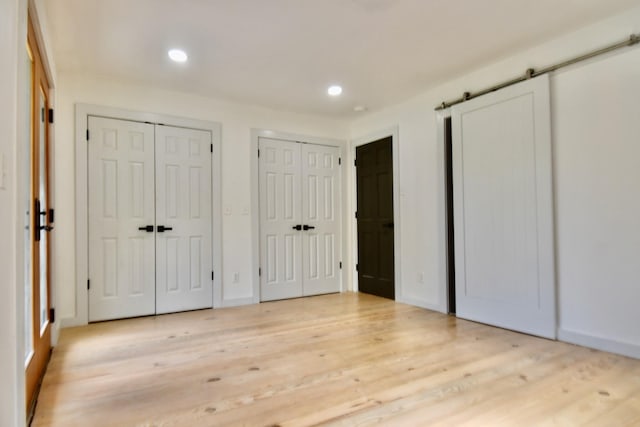 unfurnished bedroom featuring multiple closets, wood finished floors, and recessed lighting