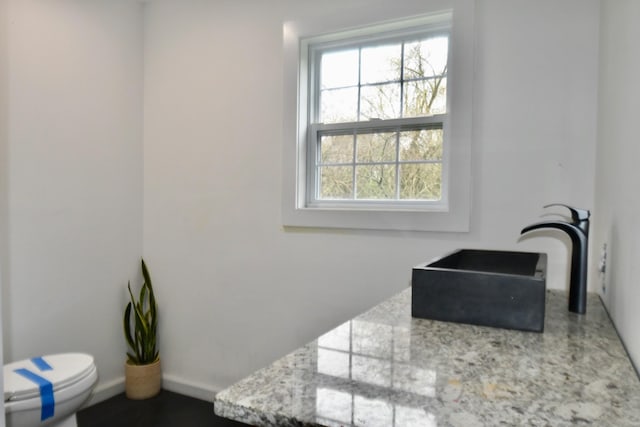 bathroom featuring toilet, a sink, and baseboards