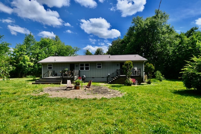back of house with crawl space, a wooden deck, a lawn, and metal roof