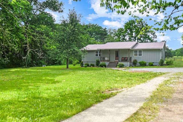 single story home with covered porch, a front lawn, metal roof, and board and batten siding